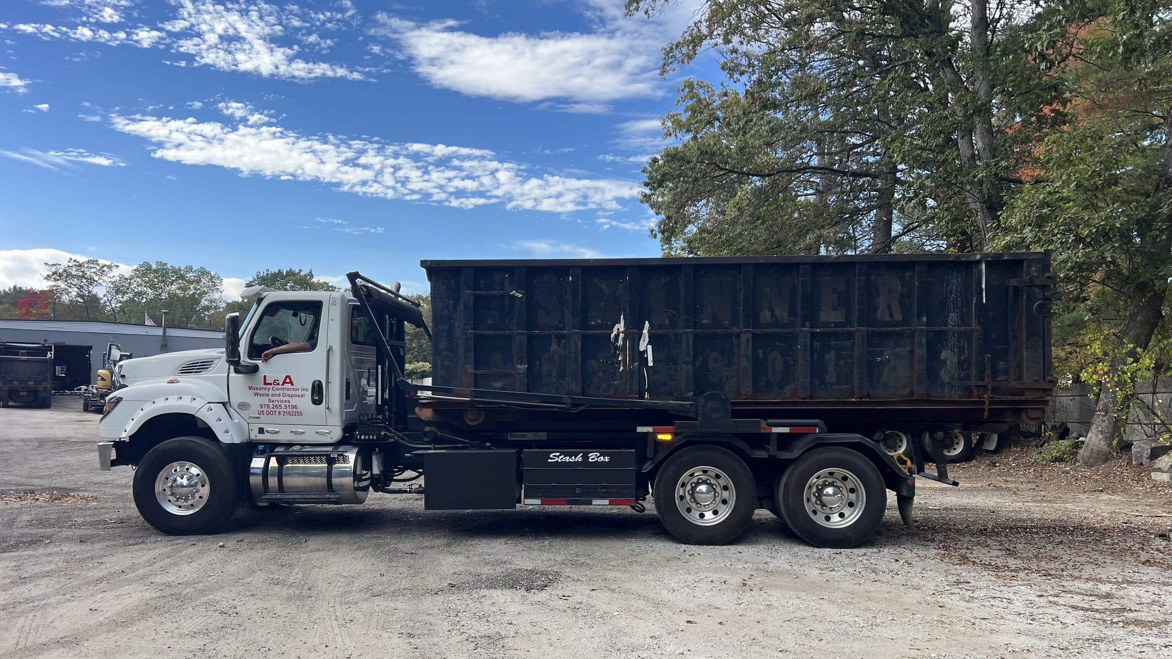 An L&A roll-off truck parked at the North Billerica yard with a container loaded.